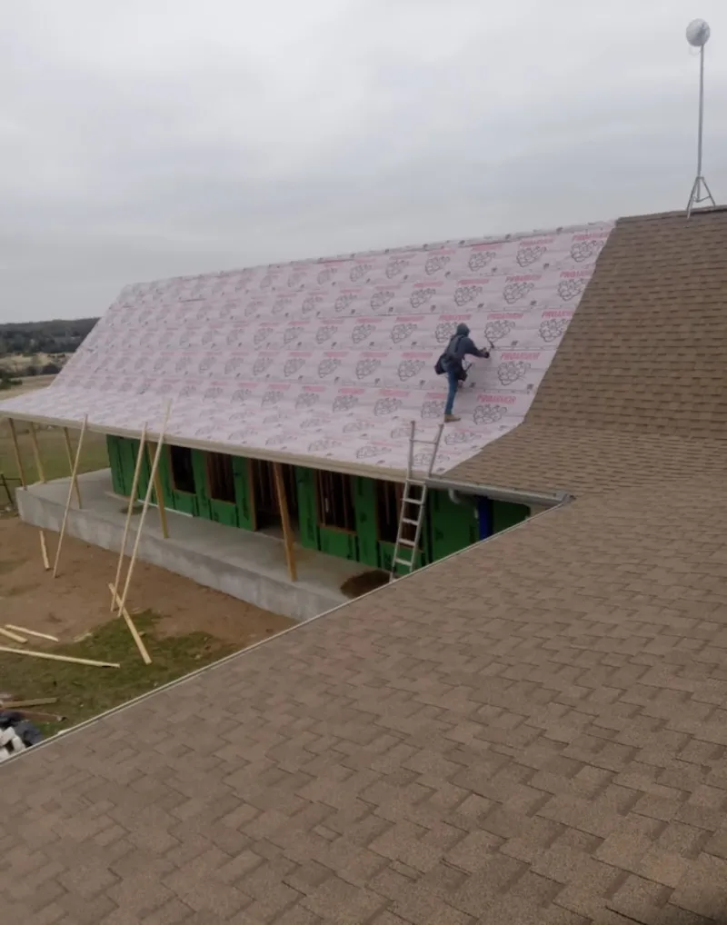Worker preparing underlayment for a metal roof installation in Cramerton